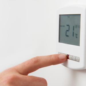 person changing the settings on their thermostat.
