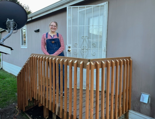 Amanda, a Skagit County homeowner standing on her recently replaced porch through the Critical Repair Program at Skagit Habitat for Humanity