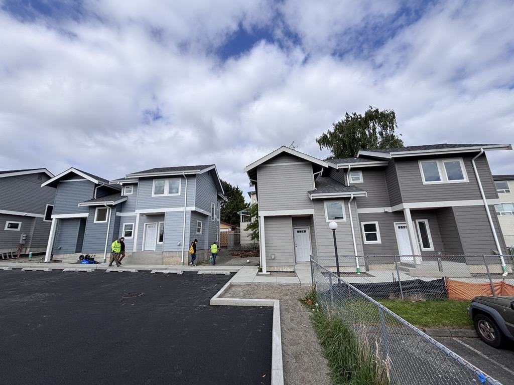 Skagit Habitat for Humanity's 8-Home Affordable Homeownership project in Anacortes, Washington. Four duplexes in different neutral shades of gray and blue.