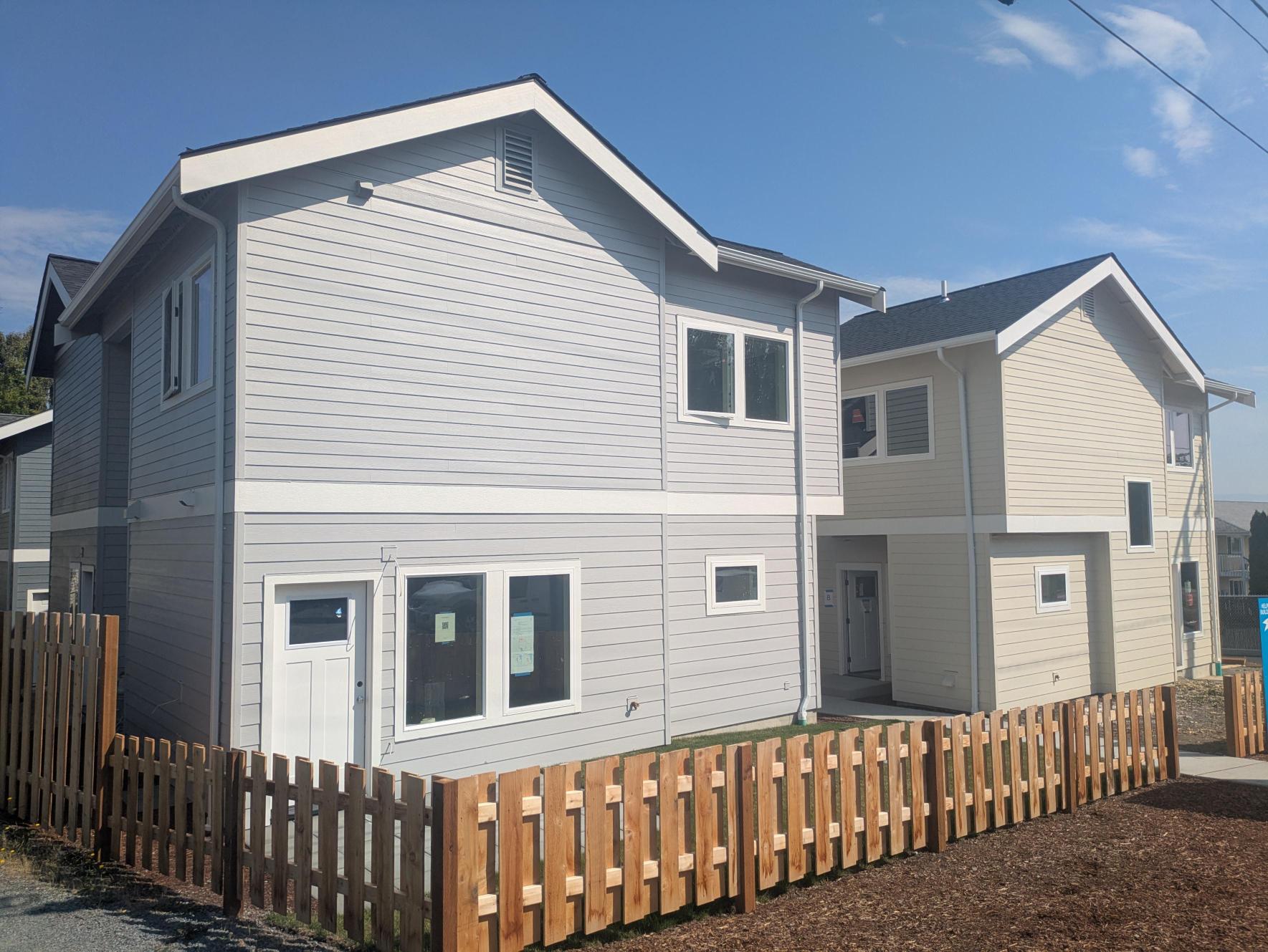 two tan and grey homes in Anacortes with a small fence around them. Homes built by Skagit Habitat for Humanity.