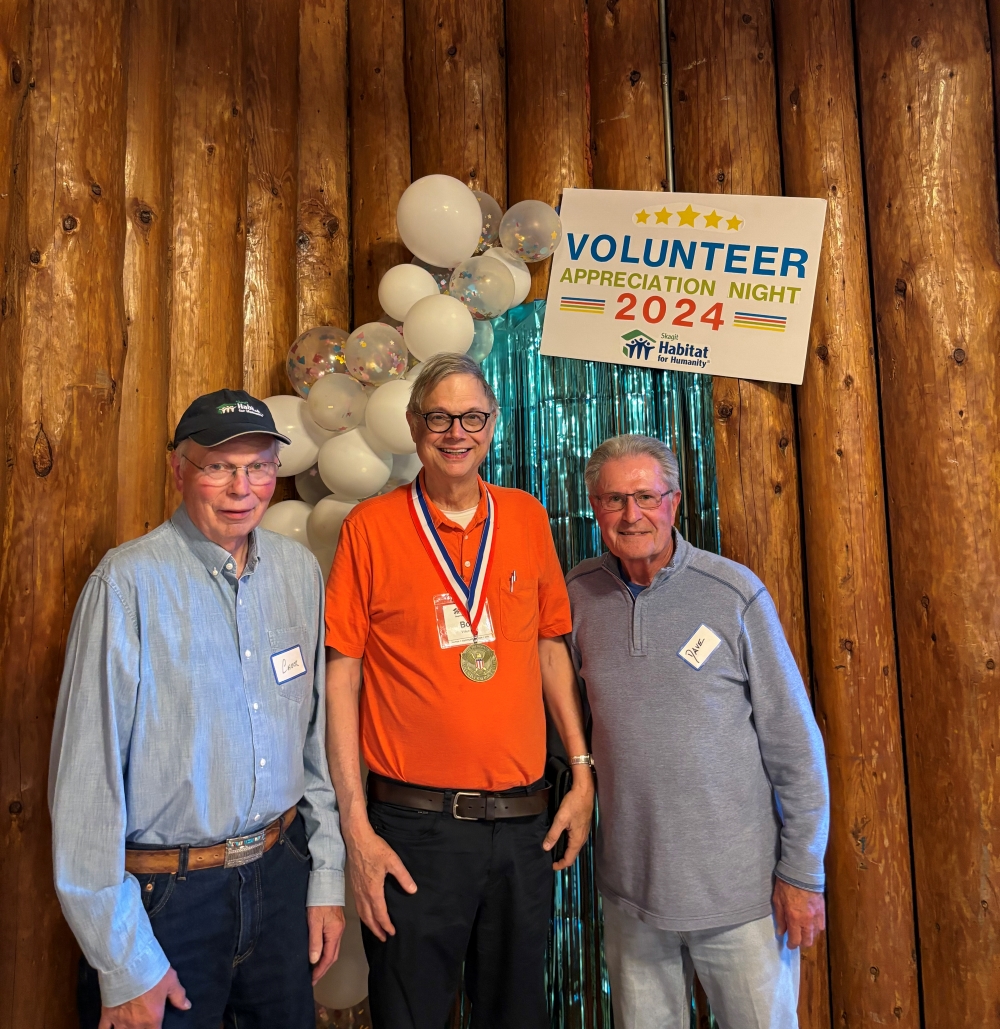 Chuck, Bob, and Dave standing in front of the volunteer appreciation night sign.