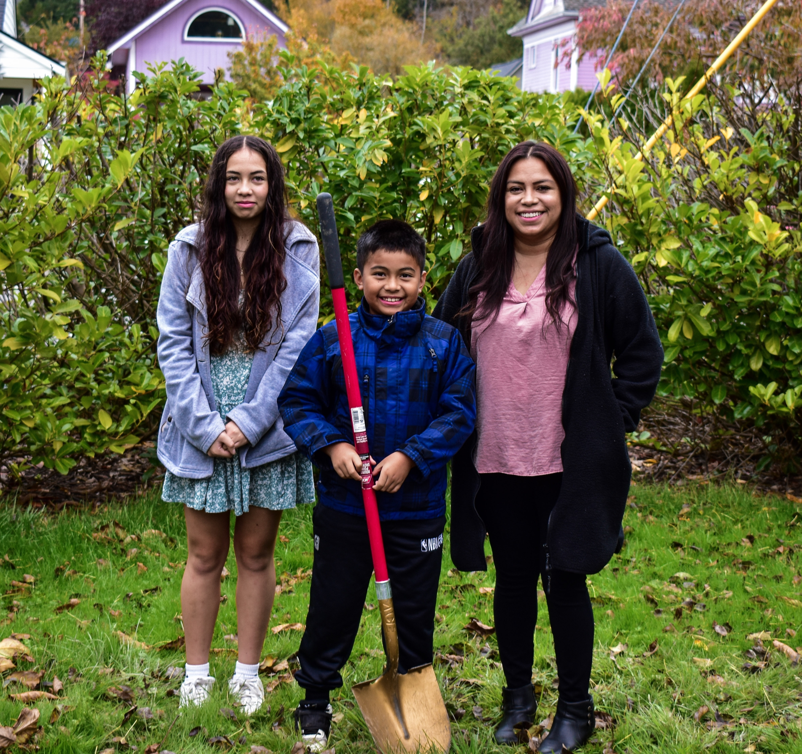 rocio and family with gold shovel Mom, daughter, and son standing on the future location of their home at their groundbreaking ceremony in La Conner.